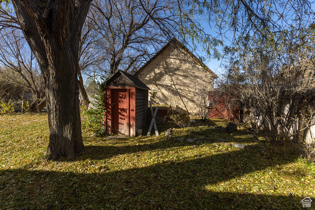 View of side of home with a yard and a storage shed