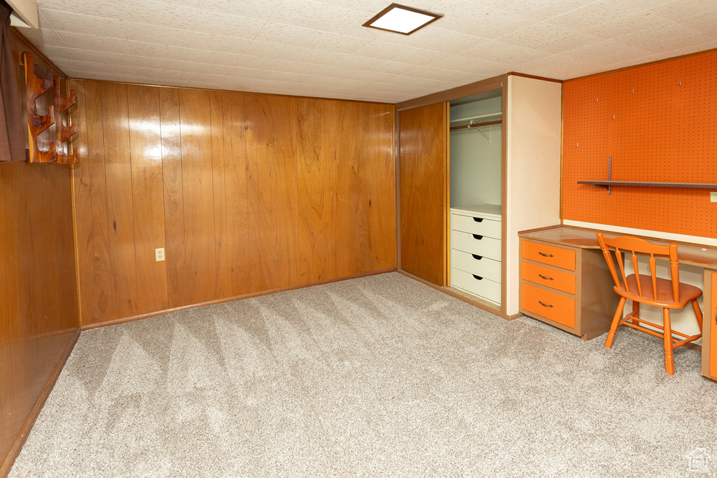 Unfurnished office featuring light colored carpet and wooden walls