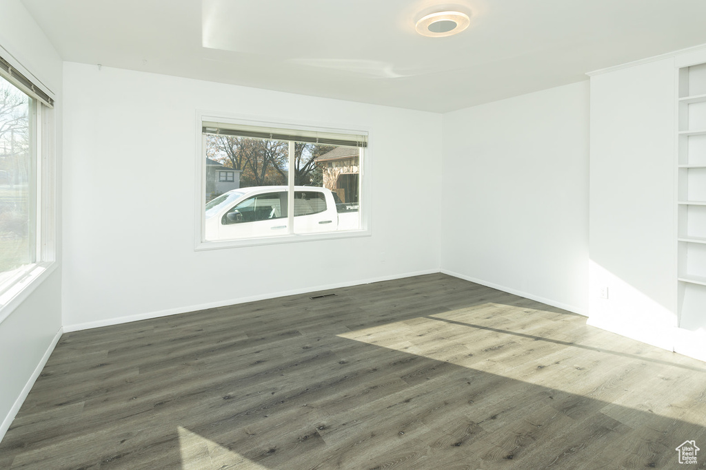 Unfurnished room with built in shelves and dark hardwood / wood-style flooring