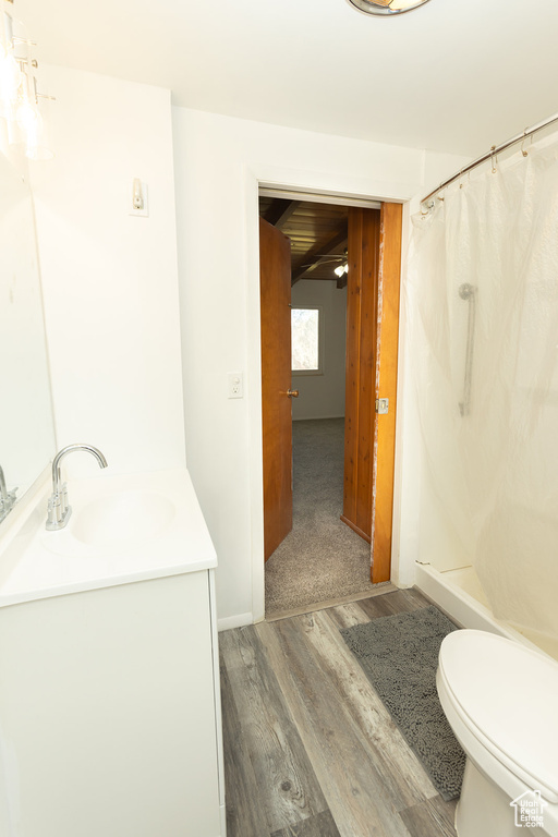 Bathroom with ceiling fan, walk in shower, toilet, vanity, and hardwood / wood-style flooring