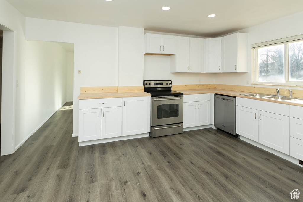 Kitchen with wooden counters, stainless steel appliances, dark wood-type flooring, sink, and white cabinets
