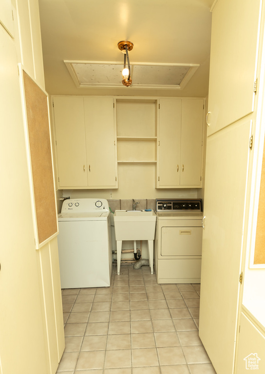 Laundry area featuring cabinets, light tile patterned floors, washer / clothes dryer, and sink