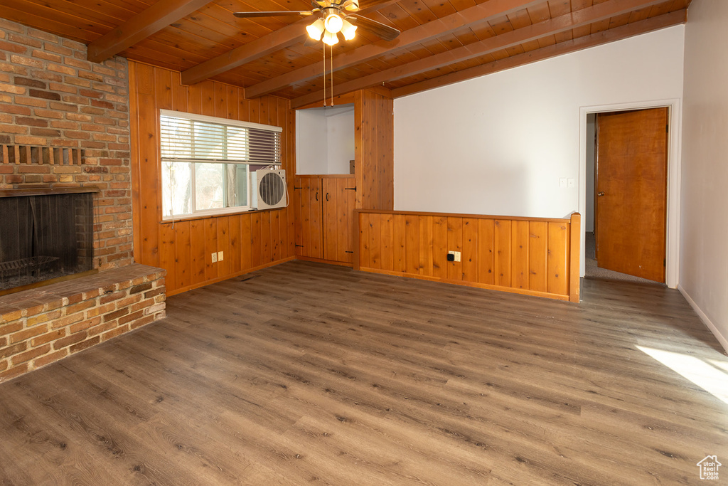 Unfurnished living room featuring beamed ceiling, hardwood / wood-style flooring, a brick fireplace, and wooden ceiling