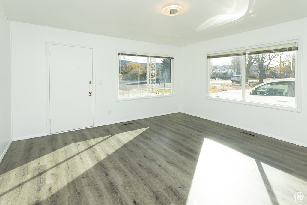 Empty room featuring dark hardwood / wood-style flooring and plenty of natural light