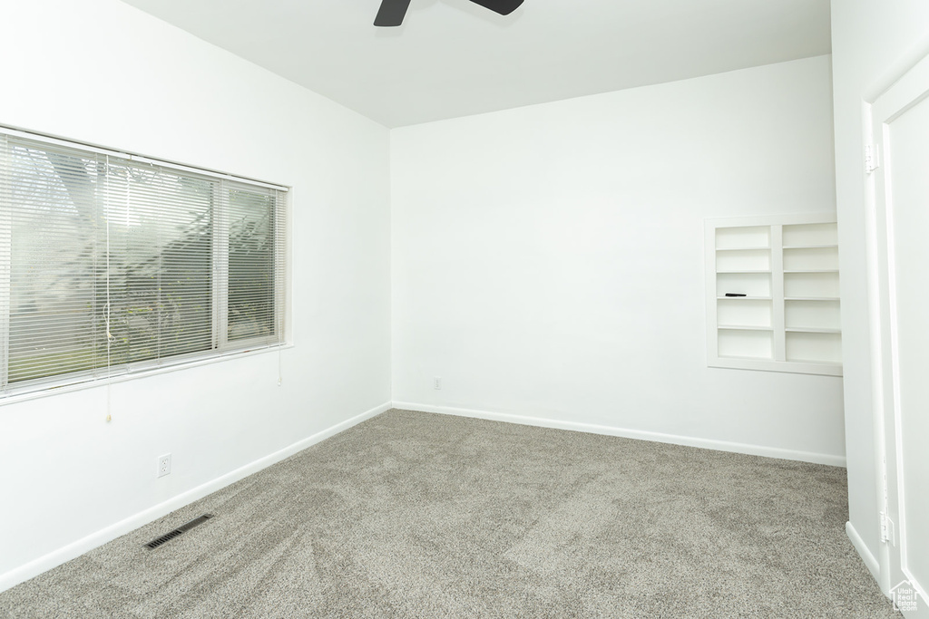 Carpeted empty room featuring ceiling fan