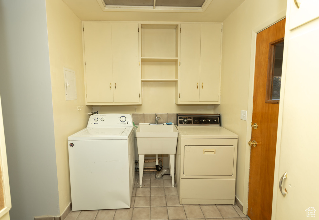 Washroom featuring cabinets, independent washer and dryer, sink, and light tile patterned flooring