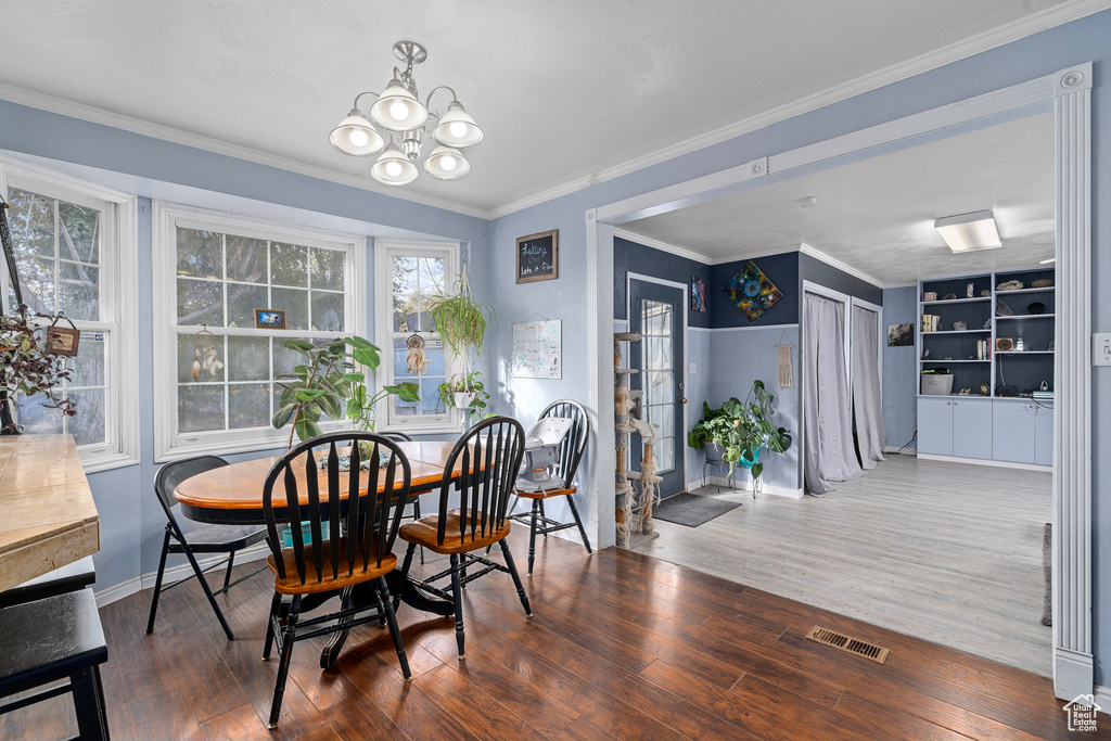 Dining space with crown molding, dark hardwood / wood-style floors, and an inviting chandelier