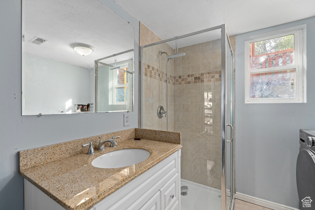 Bathroom with vanity, washer / dryer, and walk in shower