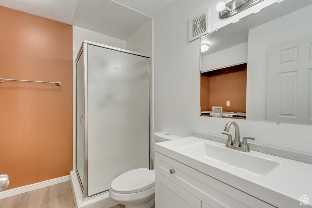 Bathroom featuring toilet, hardwood / wood-style floors, vanity, and walk in shower