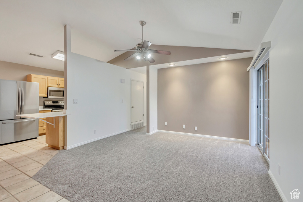 Unfurnished living room featuring light carpet, ceiling fan, and lofted ceiling