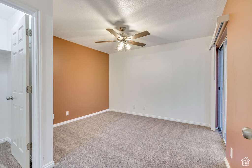 Unfurnished bedroom featuring a textured ceiling, ceiling fan, and light carpet