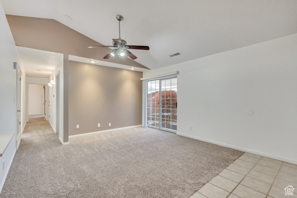 Unfurnished room with ceiling fan, light tile patterned floors, and lofted ceiling