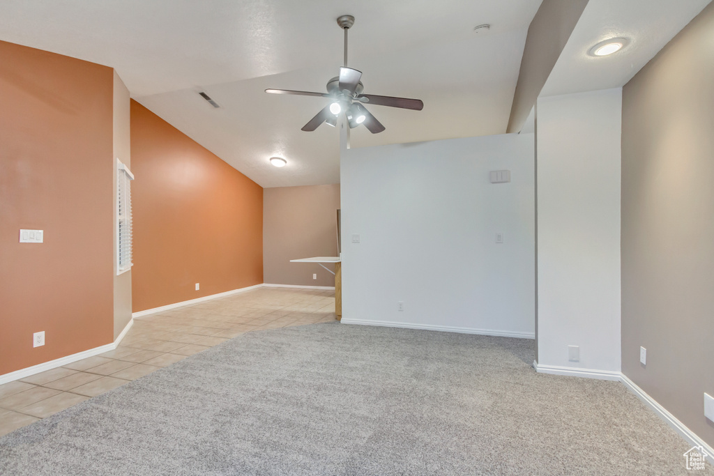 Spare room featuring ceiling fan, light tile patterned floors, and lofted ceiling