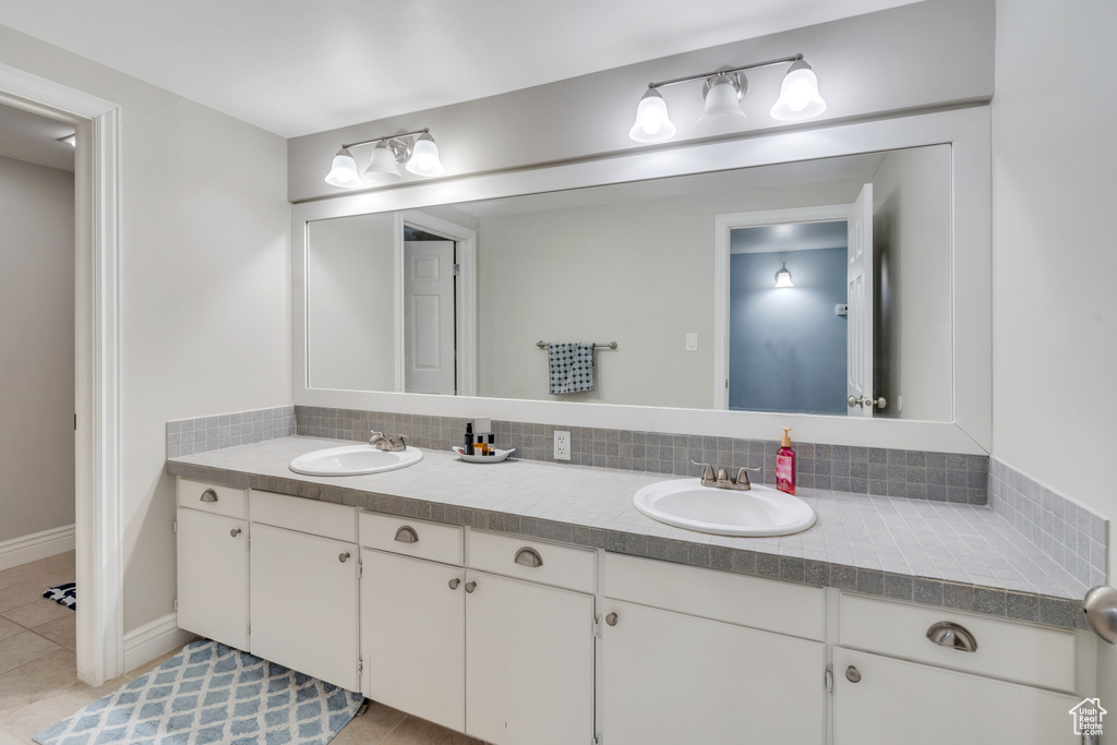 Bathroom with decorative backsplash, vanity, and tile patterned floors