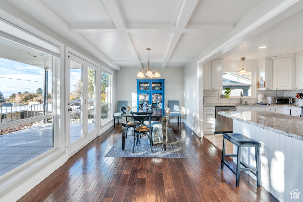 Dining room with beamed ceiling, plenty of natural light, dark hardwood / wood-style flooring, and an inviting chandelier