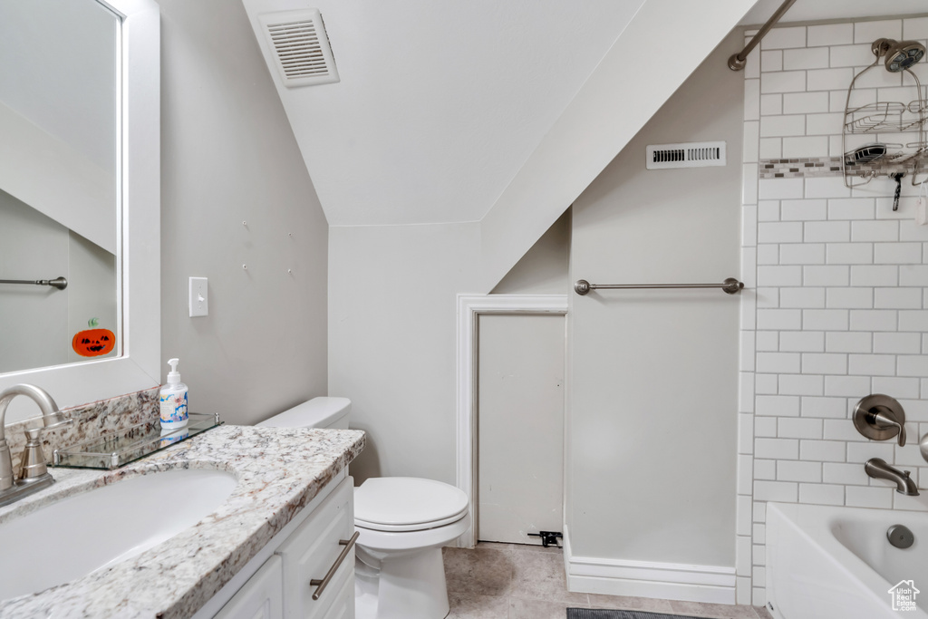 Full bathroom featuring vanity, toilet, tiled shower / bath, and vaulted ceiling