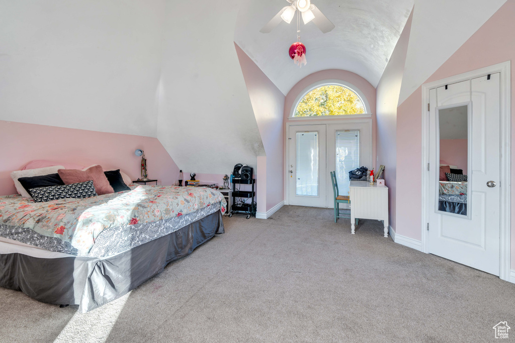 Carpeted bedroom with ceiling fan, french doors, and vaulted ceiling