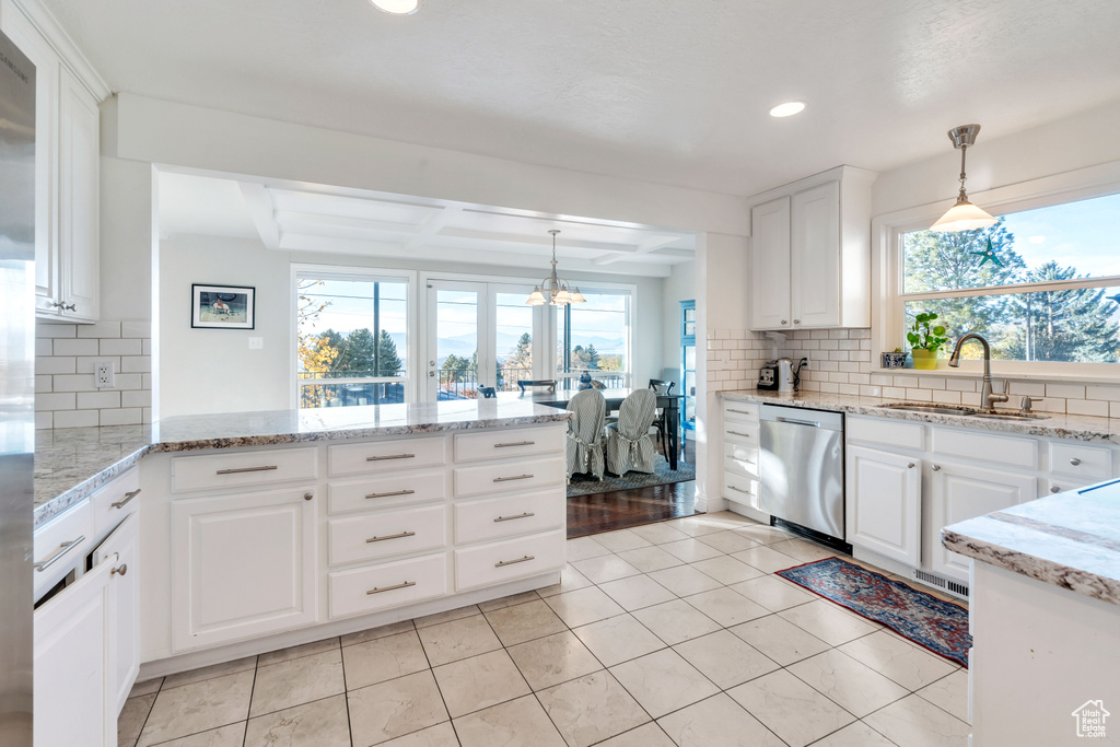 Kitchen featuring white cabinetry, sink, stainless steel dishwasher, backsplash, and decorative light fixtures