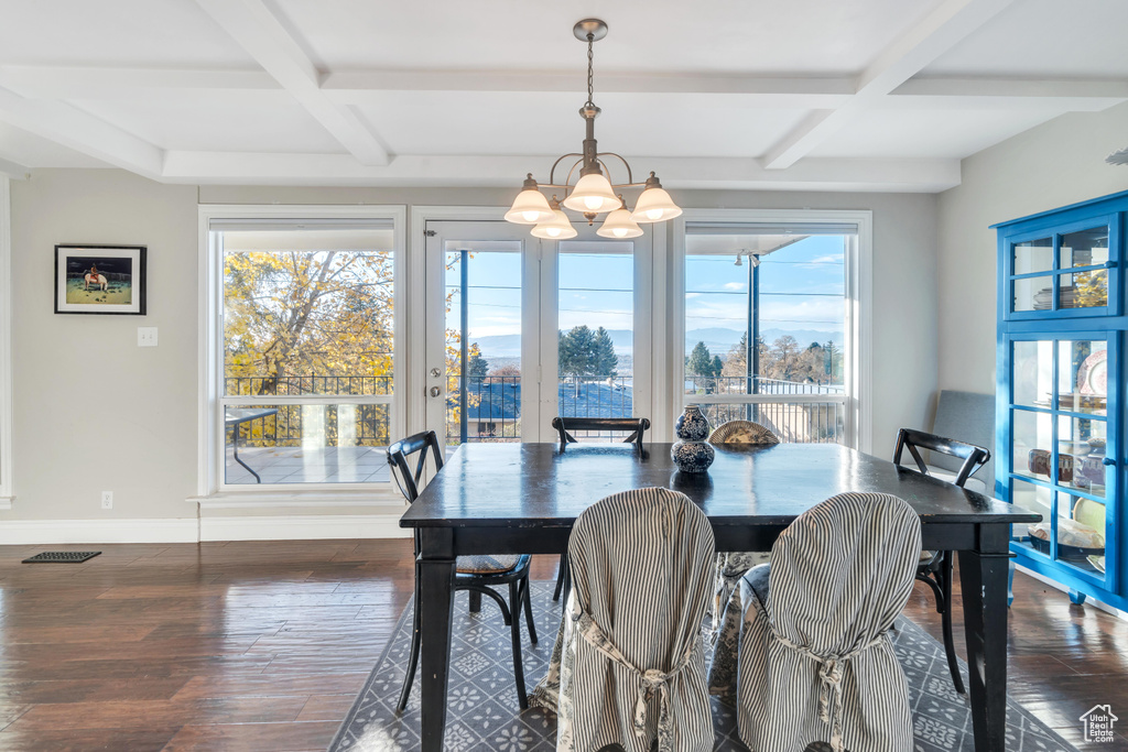 Dining area with beam ceiling, a wealth of natural light, and dark wood-type flooring