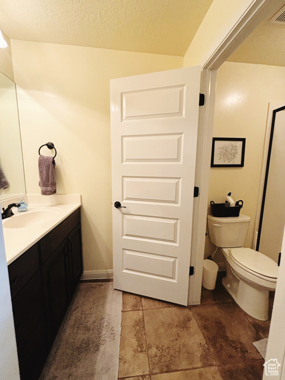 Bathroom featuring vanity, a textured ceiling, and toilet