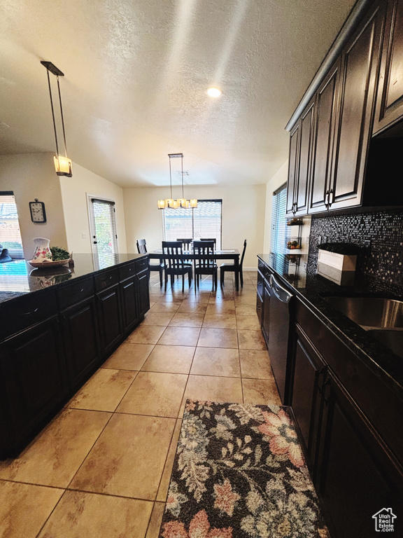 Kitchen featuring a wealth of natural light, pendant lighting, vaulted ceiling, and black dishwasher