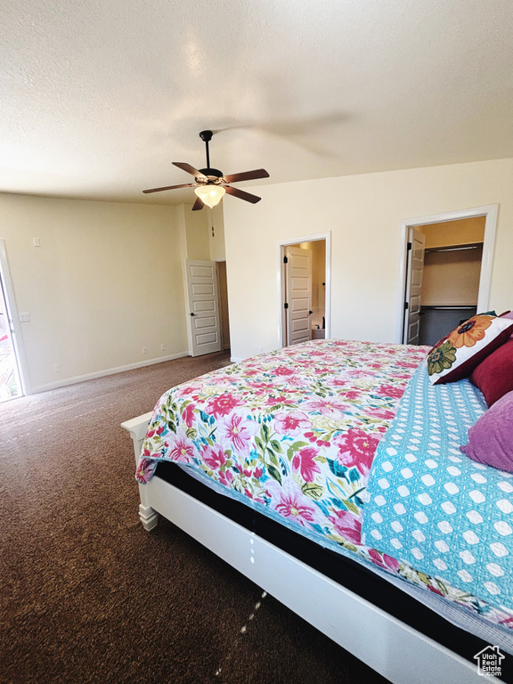 Carpeted bedroom with a textured ceiling, a walk in closet, a closet, and ceiling fan