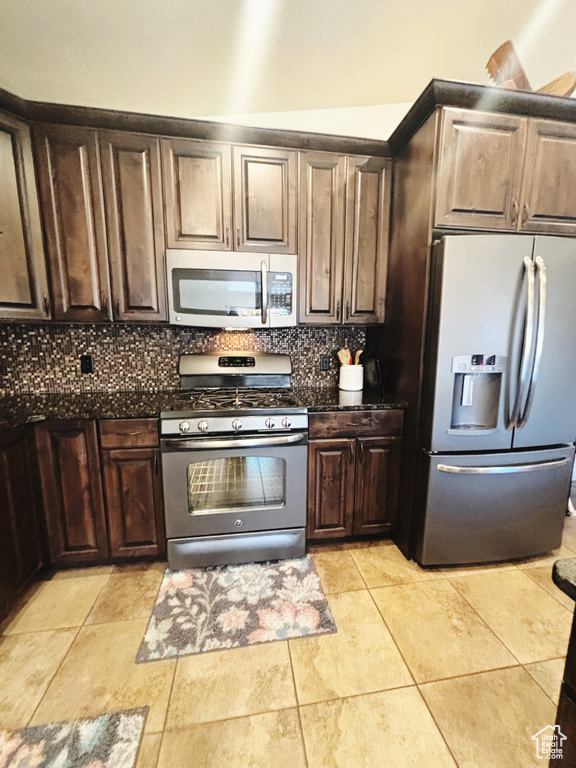 Kitchen with backsplash, dark brown cabinetry, light tile patterned floors, and stainless steel appliances