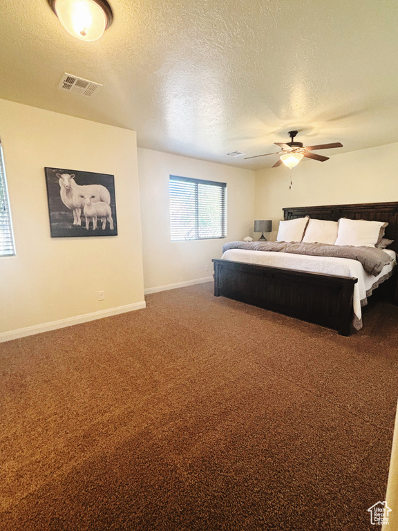 Carpeted bedroom with ceiling fan and a textured ceiling