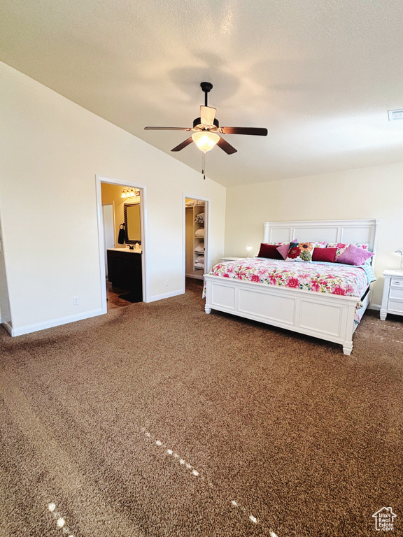 Unfurnished bedroom with ensuite bath, ceiling fan, a spacious closet, a textured ceiling, and dark carpet