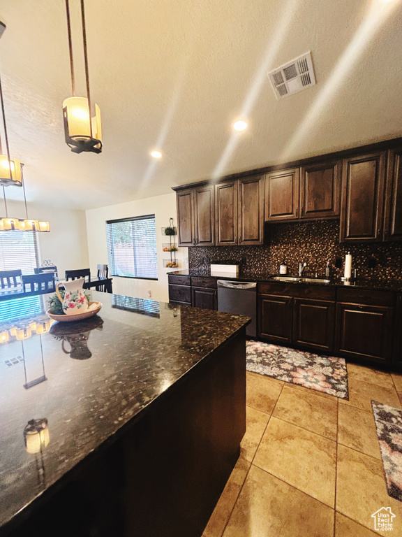 Kitchen featuring sink, stainless steel dishwasher, decorative light fixtures, decorative backsplash, and dark brown cabinets