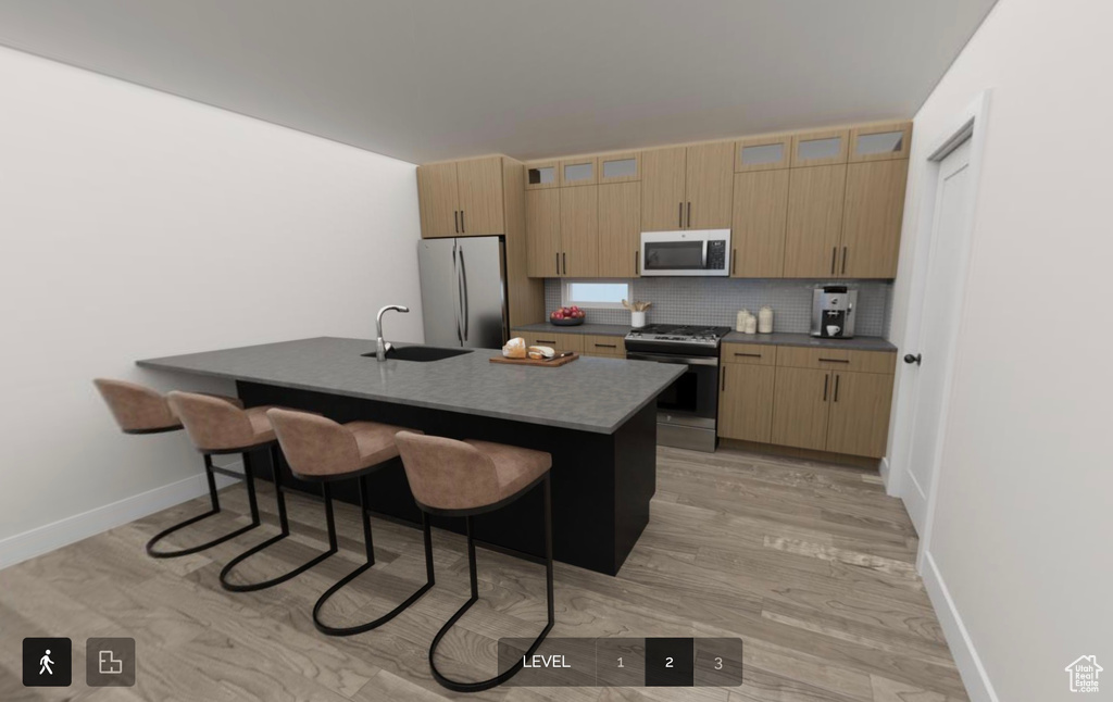 Kitchen with decorative backsplash, appliances with stainless steel finishes, light wood-type flooring, a breakfast bar, and sink