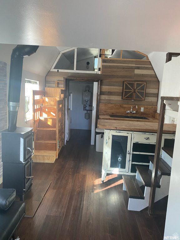 Interior space with lofted ceiling, dark hardwood / wood-style flooring, and a wood stove