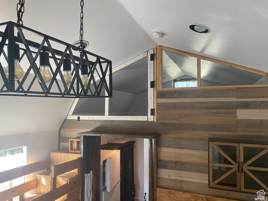 Stairway featuring vaulted ceiling and wood walls