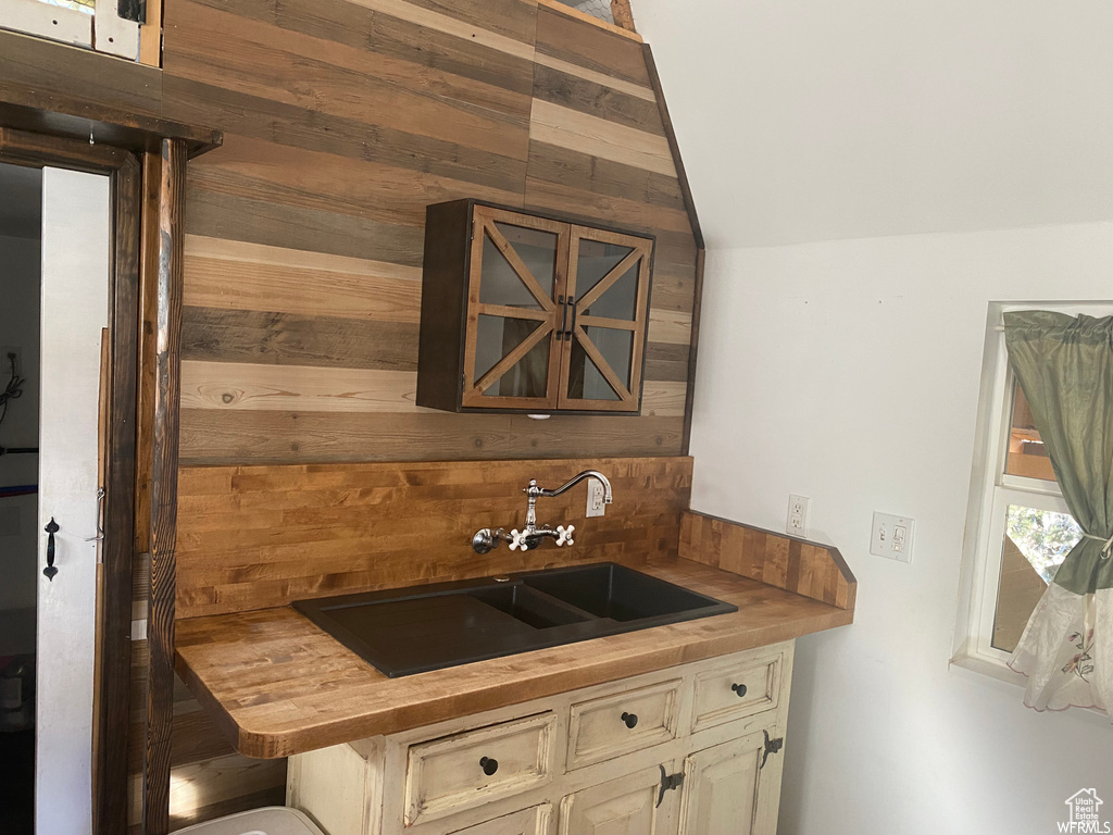 Kitchen featuring cream cabinets, sink, butcher block counters, and wood walls