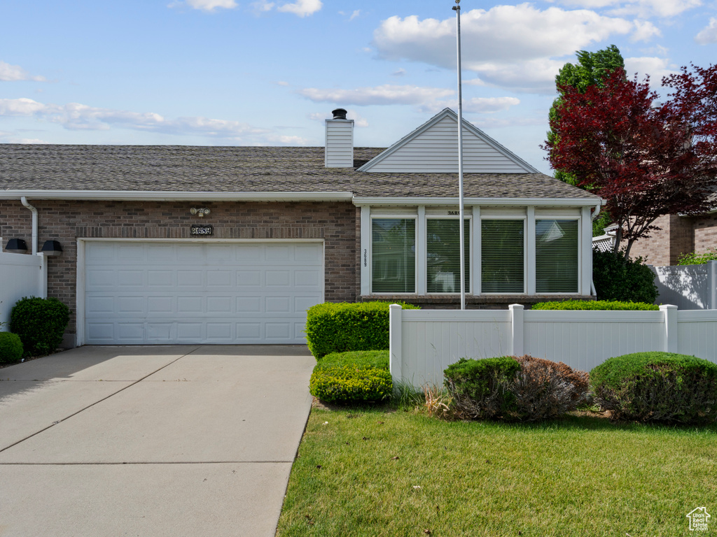 View of front facade featuring driveway, a garage, brick siding, and a chimney