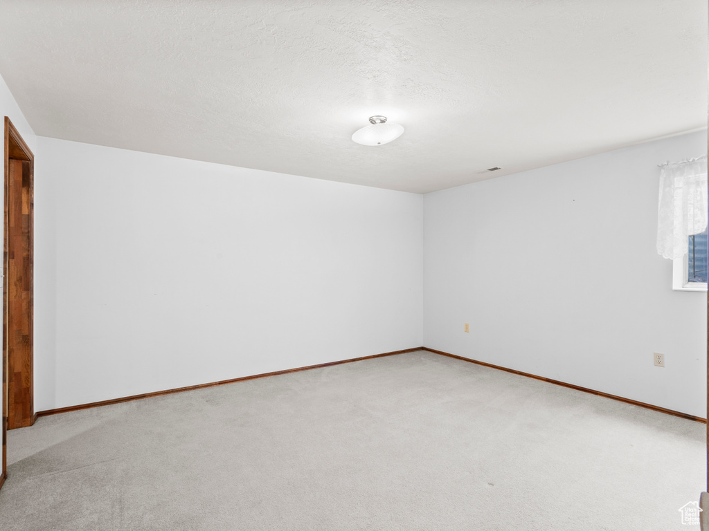 Spare room with light carpet and baseboards