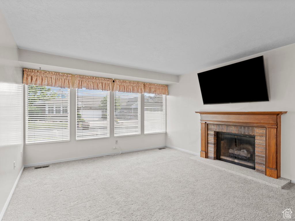 Unfurnished living room featuring carpet floors, a fireplace, and baseboards