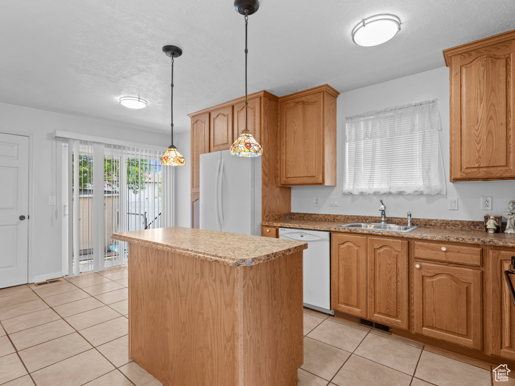 Kitchen with white appliances, a center island, a sink, light tile patterned floors, and a textured ceiling