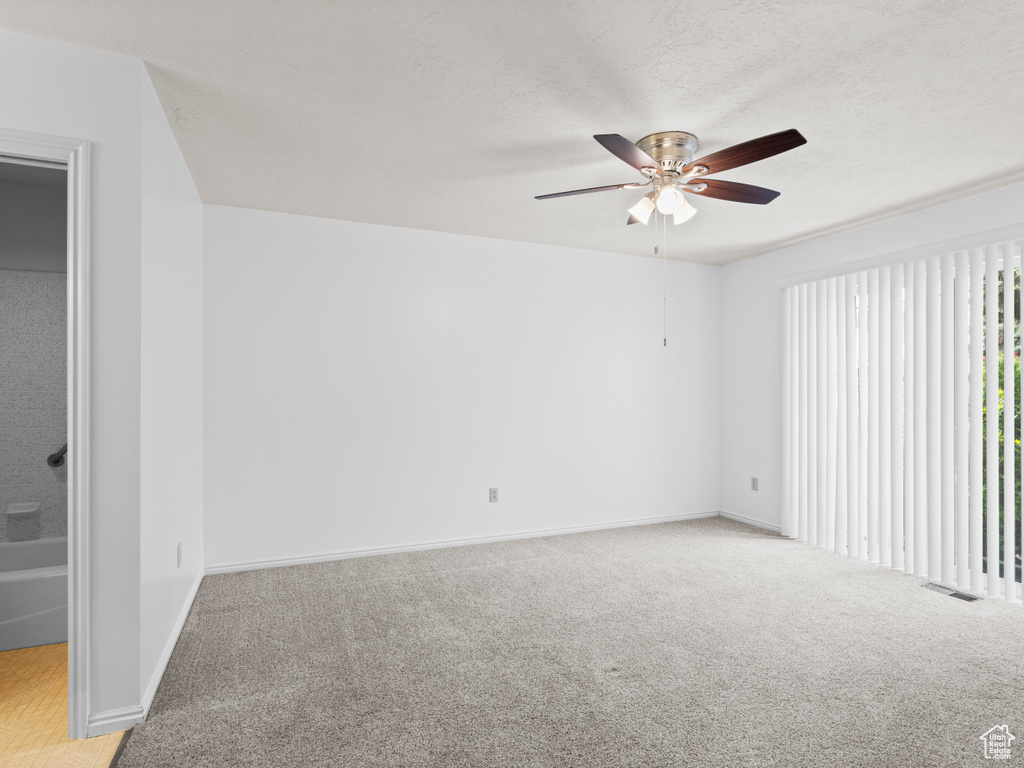 Carpeted spare room featuring a ceiling fan and baseboards