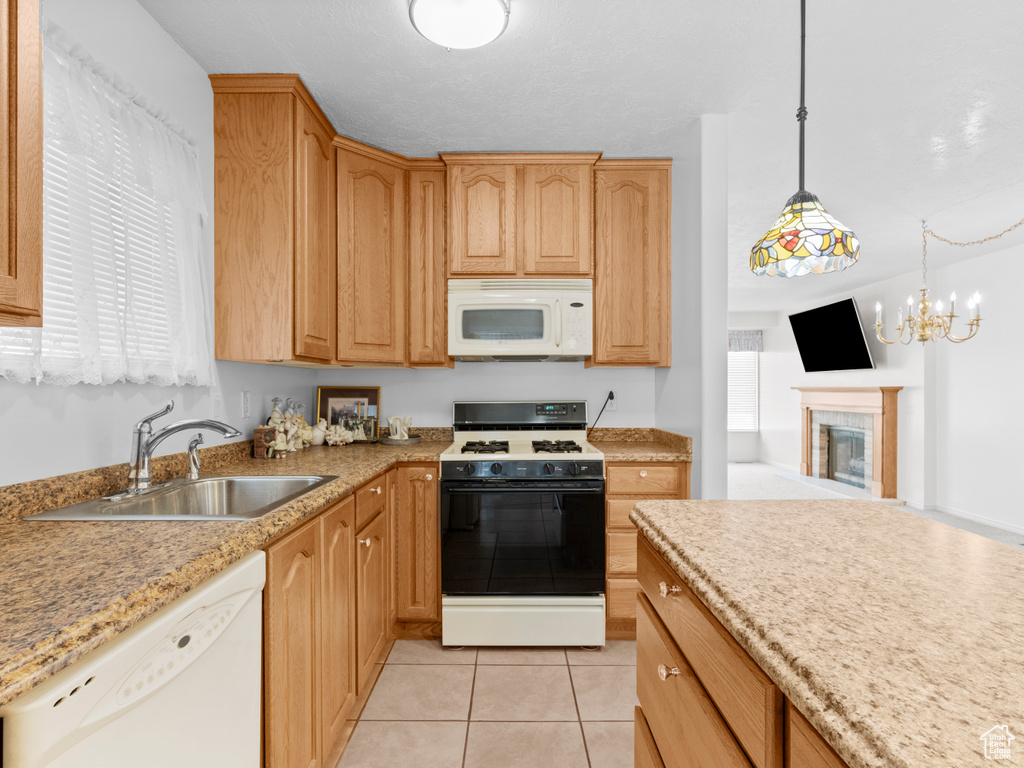 Kitchen with white appliances, a sink, light tile patterned floors, pendant lighting, and a chandelier