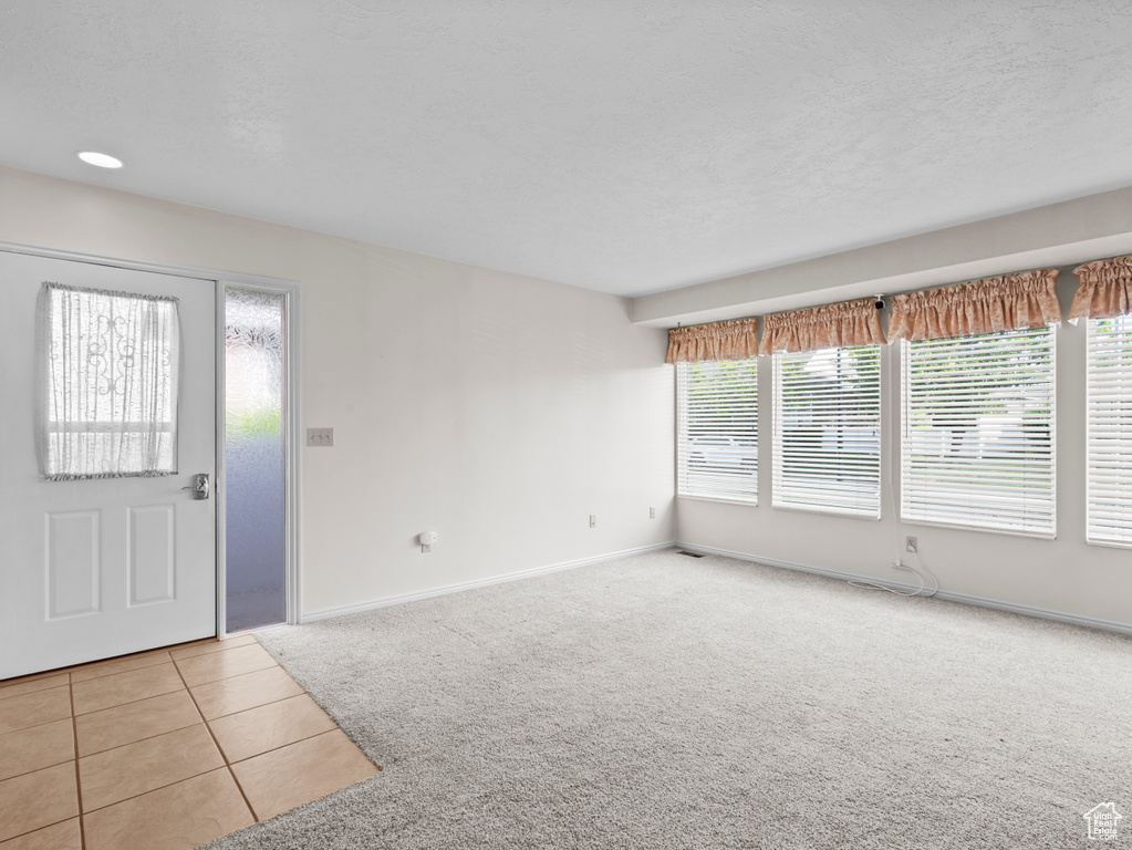 Foyer featuring light carpet, light tile patterned floors, and baseboards