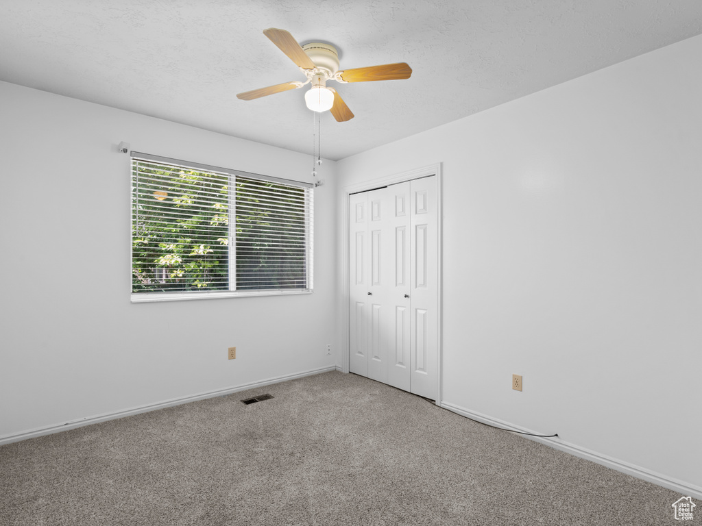 Unfurnished bedroom with carpet flooring, baseboards, a closet, and ceiling fan