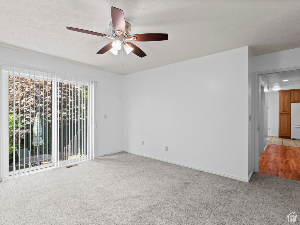 Empty room featuring ceiling fan, light colored carpet, and baseboards