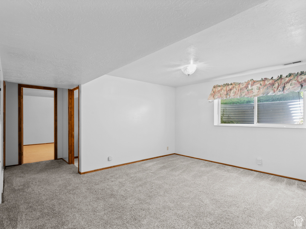 Spare room featuring carpet flooring, a textured ceiling, and baseboards