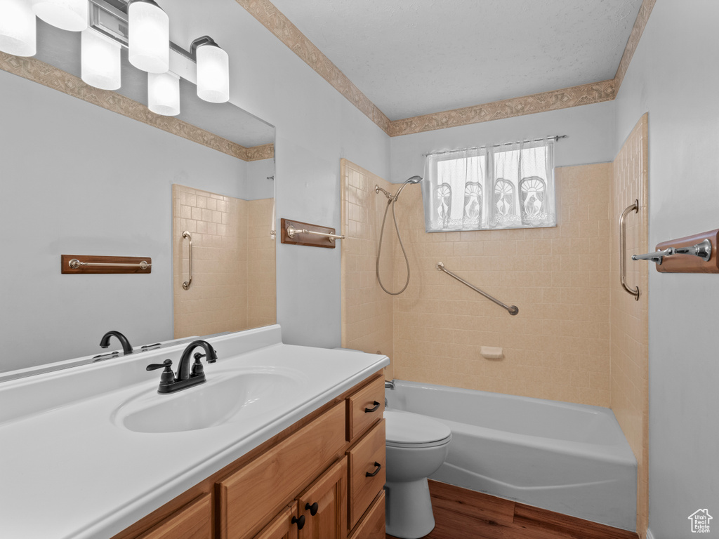 Bathroom featuring wood finished floors, vanity, shower / tub combination, and toilet