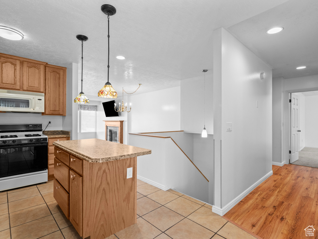 Kitchen featuring range with gas cooktop, white microwave, a center island, light countertops, and recessed lighting
