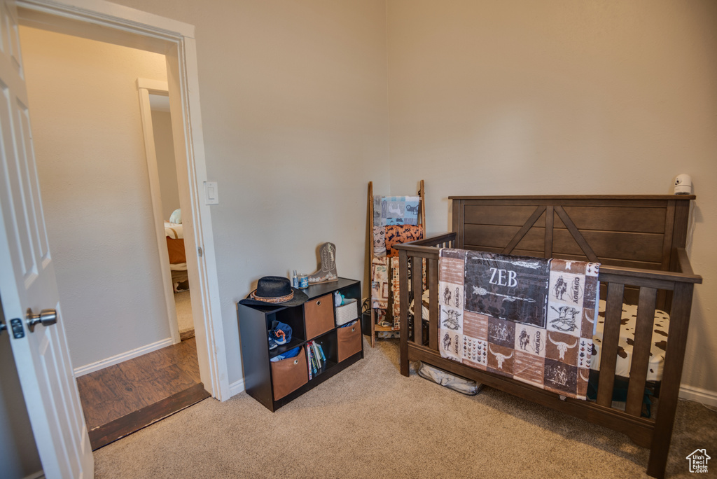 Carpeted bedroom featuring a crib