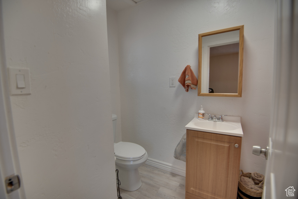 Bathroom featuring hardwood / wood-style flooring, vanity, and toilet