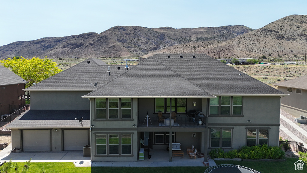 Back of house with a balcony, stucco siding, and a shingled roof