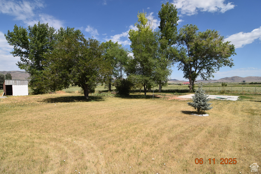 View of green lawn with a view of countryside, a mountain view, and a storage shed